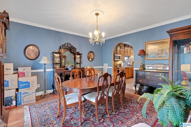 dining room featuring ornamental molding, an inviting chandelier, and light hardwood / wood-style floors