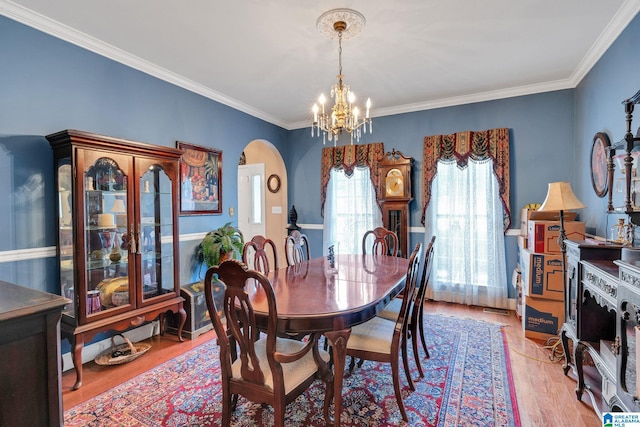 dining room with an inviting chandelier, crown molding, and light hardwood / wood-style floors