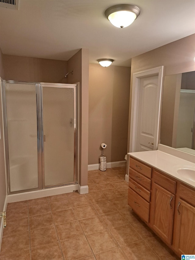 bathroom featuring a shower stall, vanity, tile patterned flooring, baseboards, and toilet