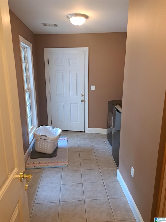 doorway to outside with baseboards, light tile patterned floors, and washing machine and clothes dryer