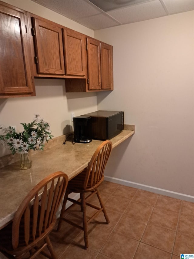 kitchen with brown cabinetry, baseboards, tile patterned floors, and light countertops