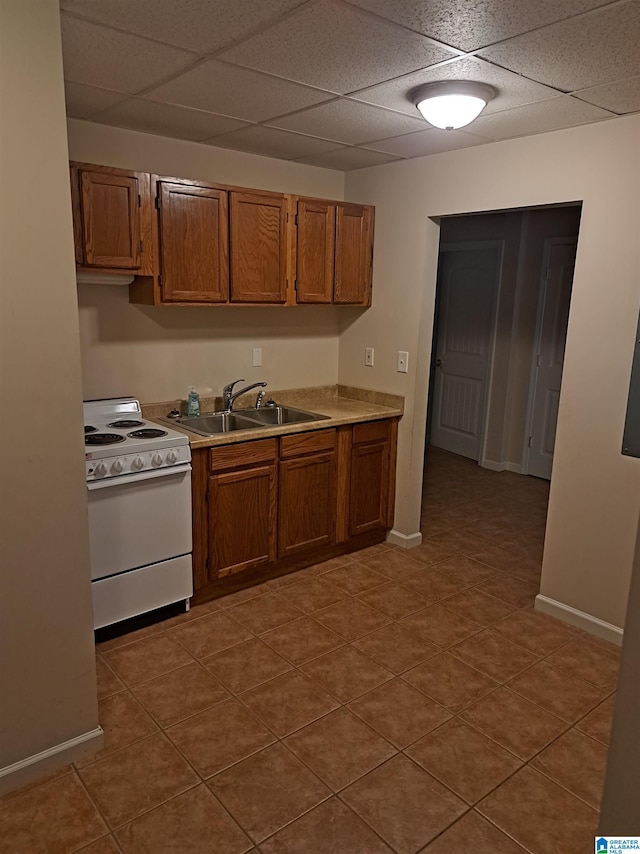 kitchen featuring white electric range, a sink, a paneled ceiling, brown cabinetry, and light countertops