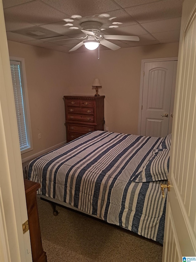 carpeted bedroom featuring a drop ceiling and ceiling fan