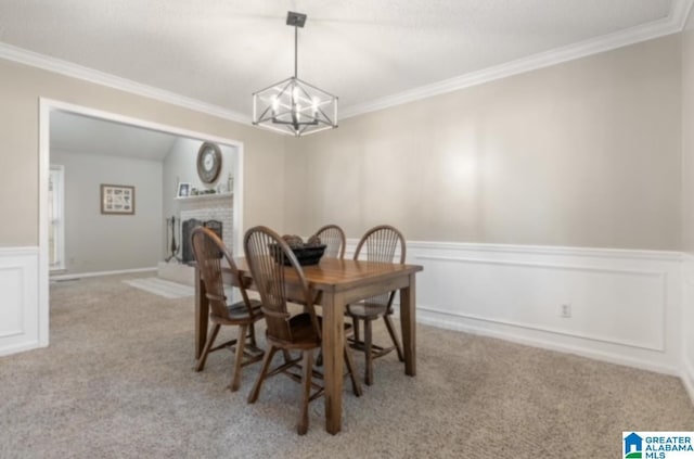 carpeted dining room with crown molding, a fireplace, and a chandelier