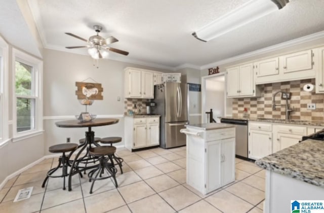 kitchen featuring sink, crown molding, a center island, stainless steel appliances, and light stone countertops