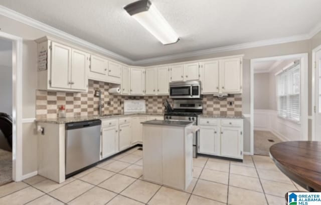 kitchen with crown molding, stainless steel appliances, white cabinets, and a kitchen island