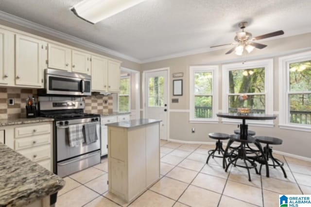 kitchen featuring ornamental molding, appliances with stainless steel finishes, a center island, and decorative backsplash