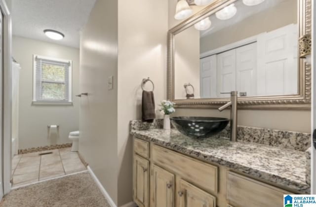 bathroom featuring tile patterned floors, vanity, toilet, and a textured ceiling