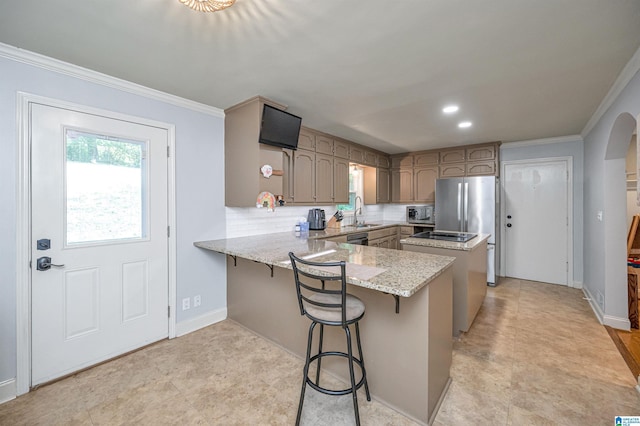 kitchen featuring tasteful backsplash, light stone counters, a peninsula, crown molding, and a sink