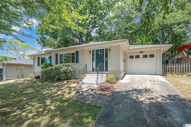 ranch-style house with an attached garage, fence, brick siding, a front lawn, and driveway