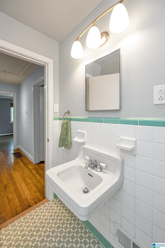 bathroom featuring tile patterned floors, wainscoting, tile walls, and visible vents