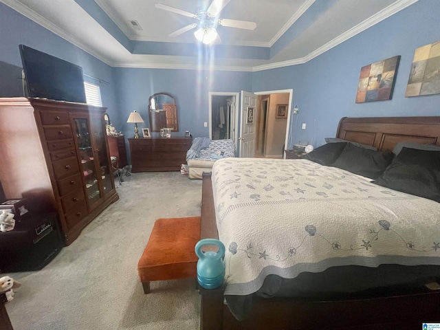 carpeted bedroom with a walk in closet, ornamental molding, a tray ceiling, a closet, and ceiling fan