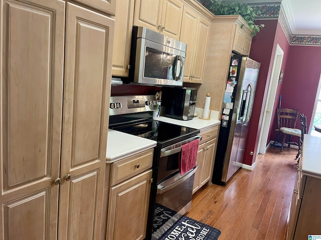 kitchen with ornamental molding, stainless steel appliances, and light wood-type flooring