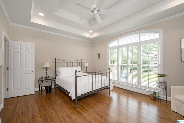 bedroom with ceiling fan, wood-type flooring, ornamental molding, and a raised ceiling