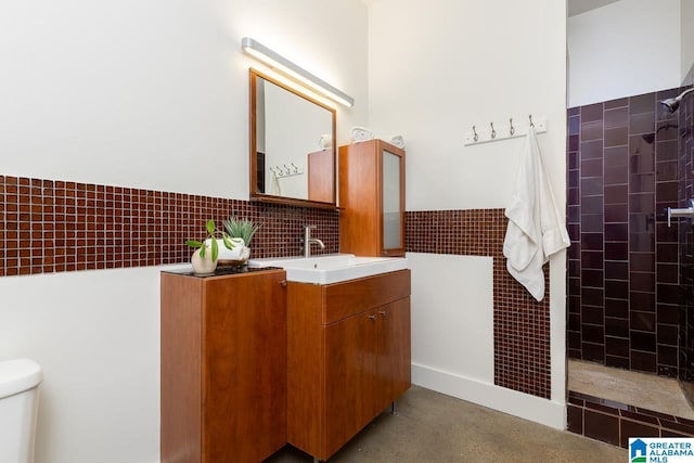 bathroom featuring tiled shower, vanity, and toilet