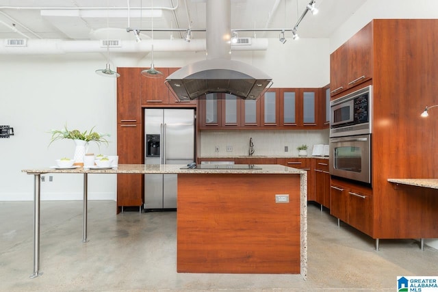 kitchen featuring stainless steel appliances, a center island, light stone countertops, decorative backsplash, and exhaust hood