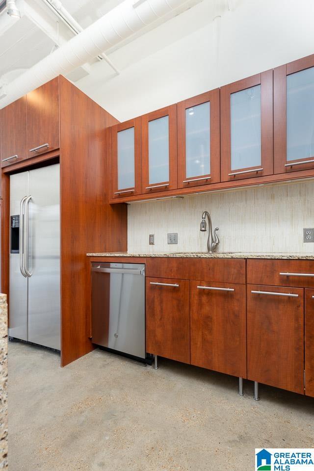 kitchen featuring light stone counters, stainless steel appliances, and sink