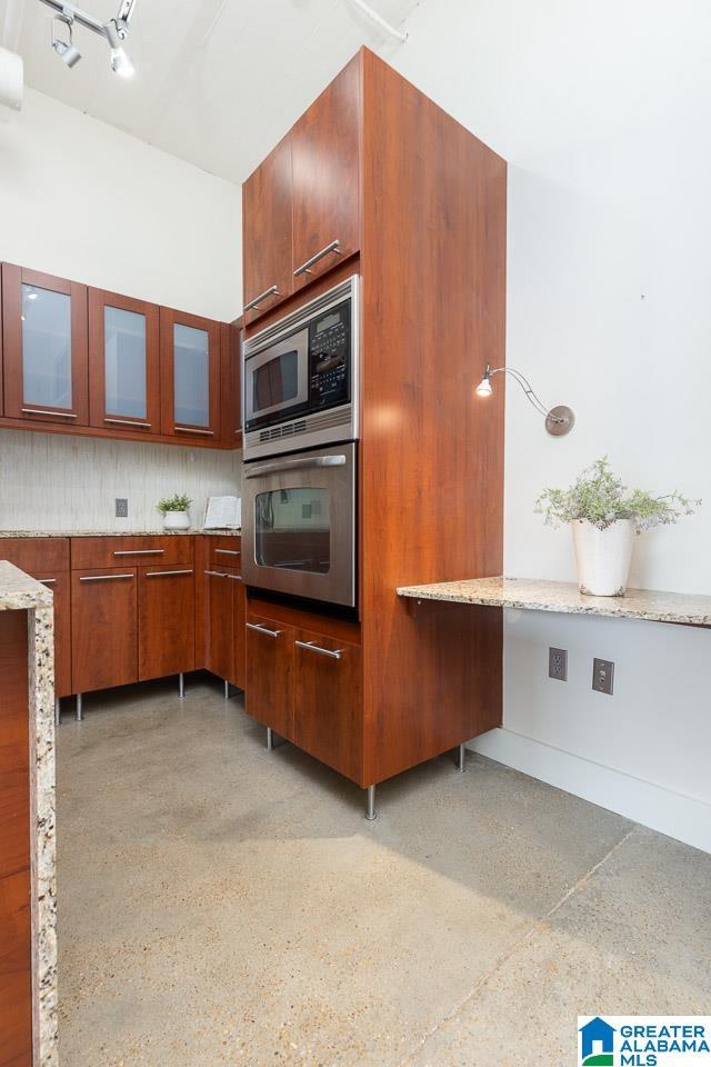 kitchen with light stone counters, stainless steel appliances, and tasteful backsplash