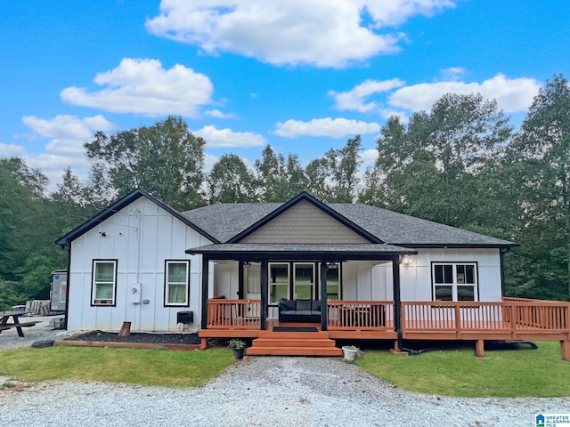 view of front of property featuring a front yard, board and batten siding, and roof with shingles