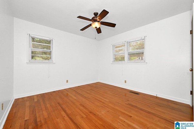 empty room featuring baseboards, a ceiling fan, visible vents, and wood finished floors