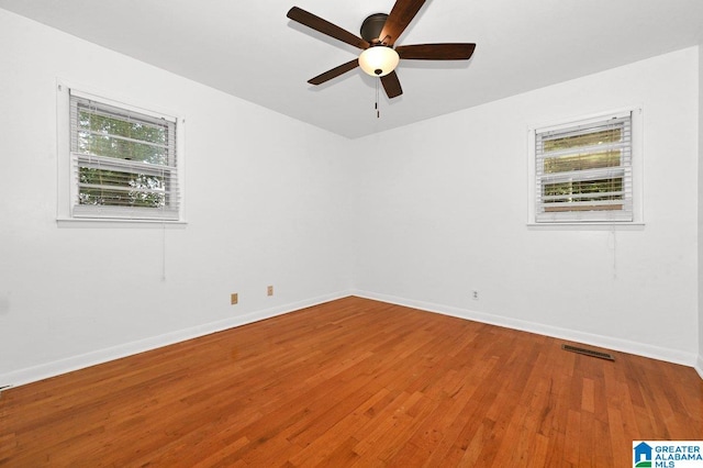 unfurnished room with visible vents, wood finished floors, baseboards, and ceiling fan
