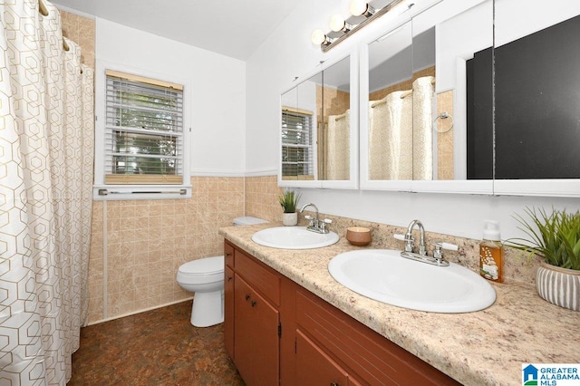 bathroom featuring a sink, double vanity, toilet, and wainscoting