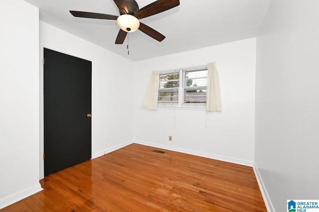 spare room featuring baseboards, visible vents, ceiling fan, and wood finished floors