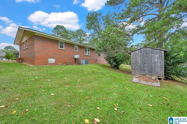 back of property with a lawn, central air condition unit, brick siding, and a storage shed