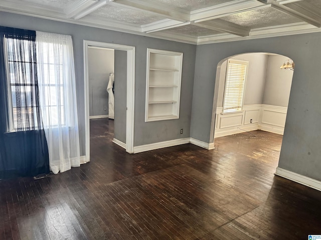 spare room with beam ceiling, coffered ceiling, dark wood-type flooring, ornamental molding, and built in shelves