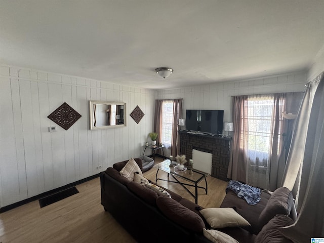 living room with a brick fireplace, a wealth of natural light, and light wood-type flooring