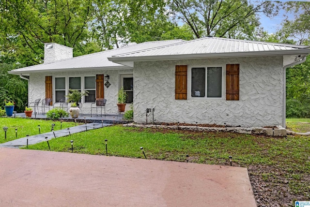 408 N Main St, Graysville, AL 35073 - view of front of house featuring stucco siding, a front yard, metal roof, a chimney, and a porch