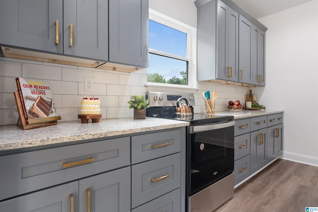 kitchen with stainless steel electric stove, light stone countertops, decorative backsplash, dark hardwood / wood-style floors, and gray cabinetry