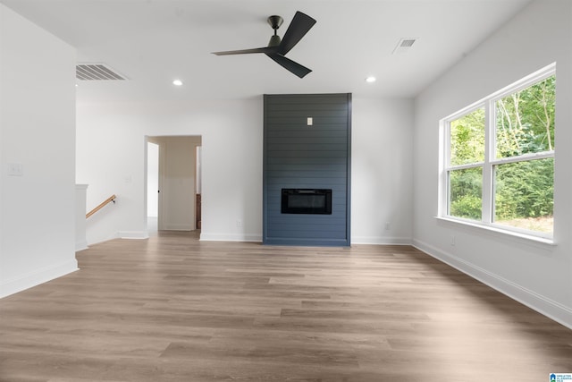 unfurnished living room with a large fireplace, ceiling fan, and light hardwood / wood-style floors