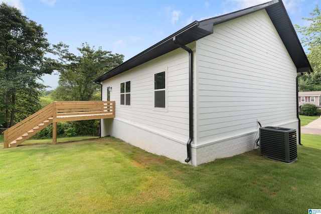 view of side of property with a yard, a deck, and central air condition unit