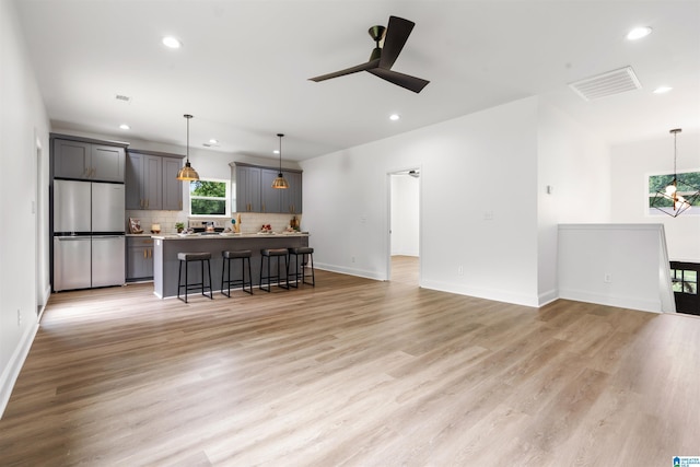 unfurnished living room featuring ceiling fan and light wood-type flooring