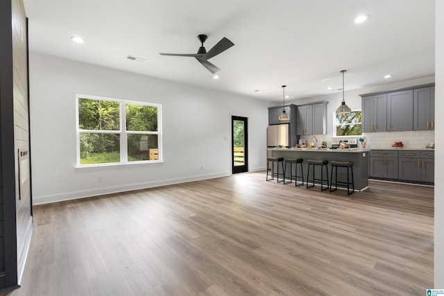 kitchen with gray cabinets, a kitchen bar, a kitchen island, decorative light fixtures, and tasteful backsplash