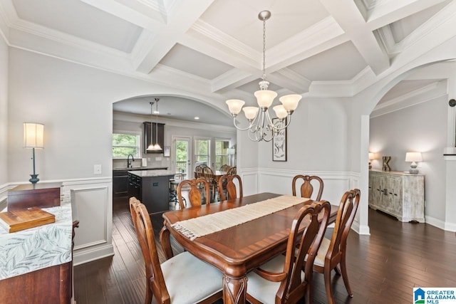 dining area featuring dark hardwood / wood-style floors, beam ceiling, ornamental molding, and a chandelier