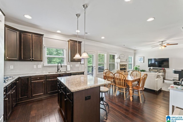 kitchen featuring ceiling fan, sink, pendant lighting, a center island, and a breakfast bar area