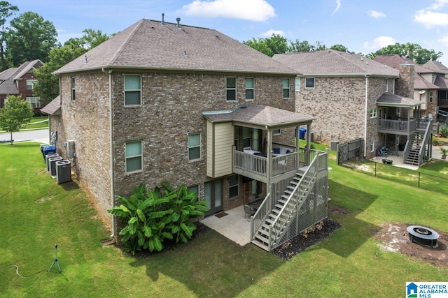 back of property featuring a deck, central air condition unit, a fire pit, a patio area, and a lawn