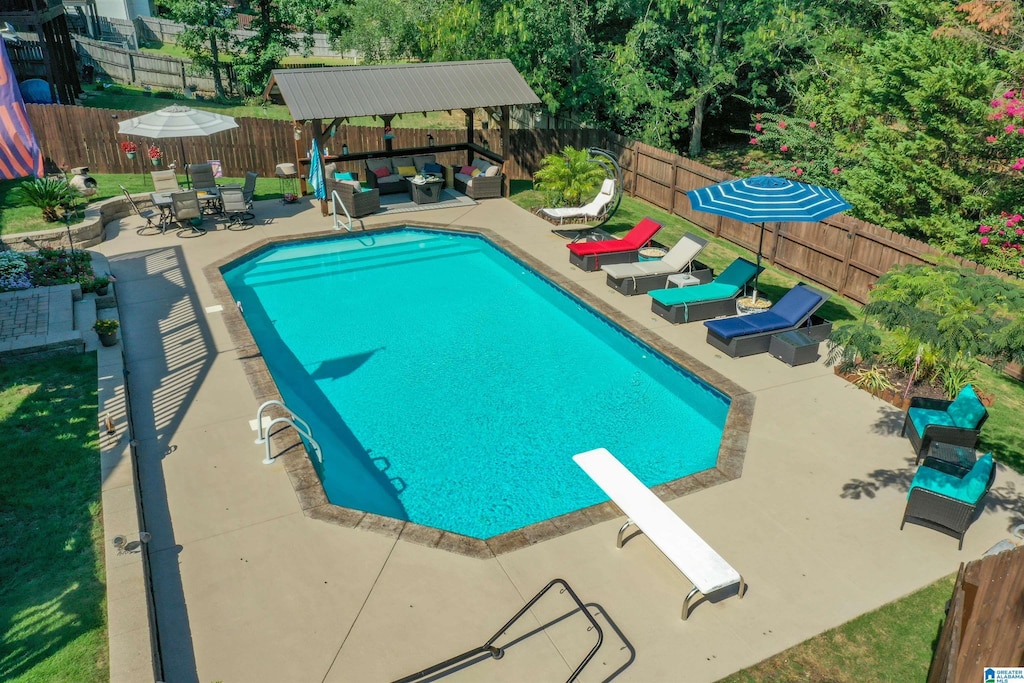 view of swimming pool featuring outdoor lounge area, a gazebo, a diving board, and a patio