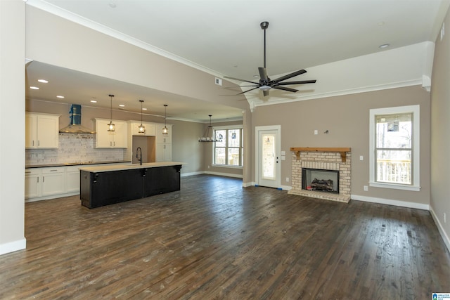 unfurnished living room with ornamental molding, dark wood finished floors, and a sink