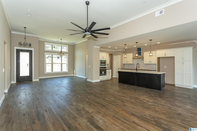 kitchen featuring wall chimney exhaust hood, visible vents, open floor plan, and a sink