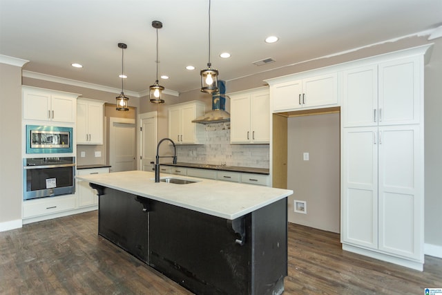 kitchen with dark wood-style floors, wall chimney exhaust hood, stainless steel appliances, and a sink