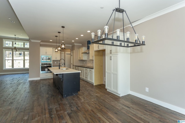 kitchen with stainless steel appliances, a sink, ornamental molding, wall chimney range hood, and backsplash