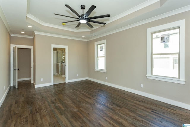 unfurnished bedroom with dark wood-style floors, a tray ceiling, ornamental molding, and baseboards