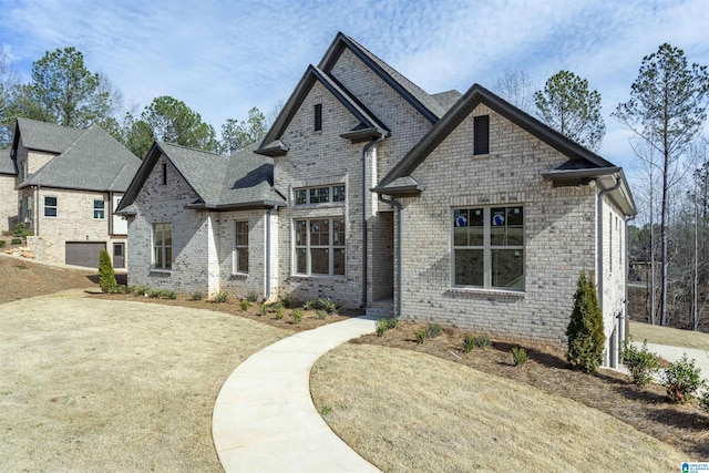 french provincial home with brick siding and a front lawn