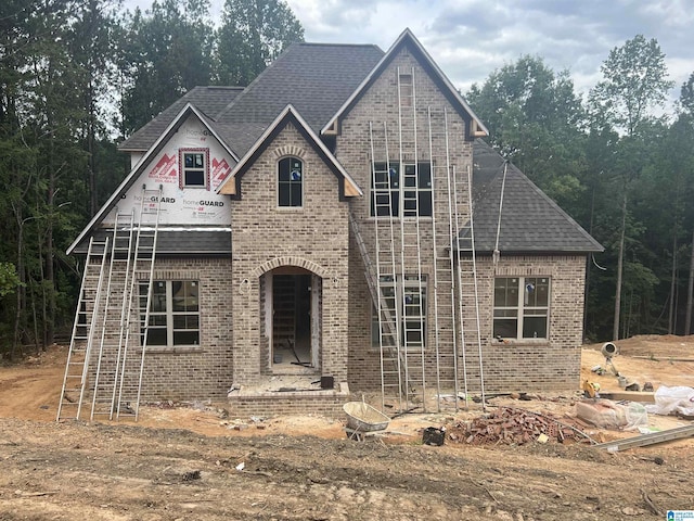 view of front facade with brick siding and roof with shingles