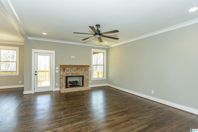 unfurnished living room featuring baseboards, dark wood finished floors, ornamental molding, a brick fireplace, and recessed lighting