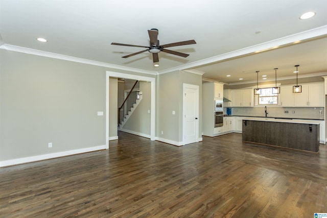 unfurnished living room with ornamental molding, dark wood finished floors, baseboards, and stairs