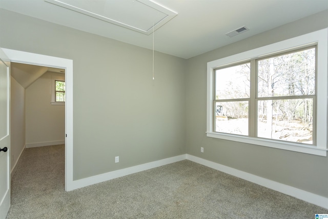 carpeted spare room featuring attic access, visible vents, and baseboards